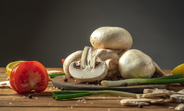 Setas, verduras, limón y especias en una mesa de madera. Concepto de ingredientes para cocinar un plato delicioso.