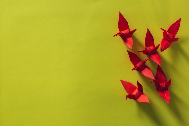 Foto sete pássaros de origami vermelhos estão voando liderando por um pássaro rosa, isolado em branco, guindaste de papel de origami vermelho