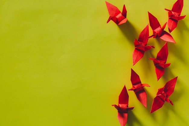 Foto sete pássaros de origami vermelhos estão voando liderando por um pássaro rosa isolado em brancogrua de papel de origami vermelho