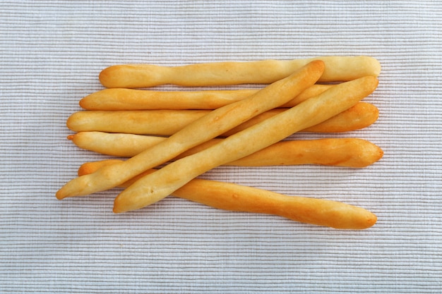 Sete varas de pão que encontram-se na toalha de mesa do algodão.