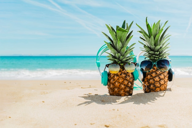 Foto setzen sie hintergrund mit den kühlen ananas auf den strand, die kopfhörer tragen