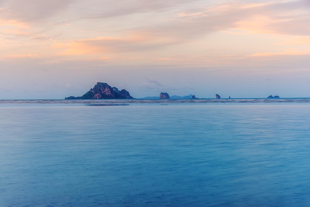 Setzen Sie Sonnenuntergang oder Sonnenaufgang mit buntem des Wolkenhimmels und -sonnenlichts auf den Strand