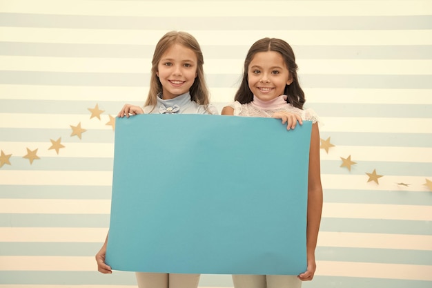 Seu anúncio em boas mãos Meninas crianças seguram espaço de cópia de cartaz de propaganda Crianças seguram banner de publicidade Crianças felizes com papel em branco para propaganda Conceito de propaganda