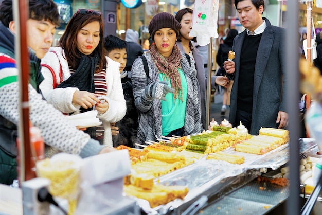 Seúl, Corea del Sur - 14 de marzo de 2016: Jóvenes coreanas que compran comida callejera en brochetas en el mercadillo abierto de Myeongdong en Seúl, Corea del Sur