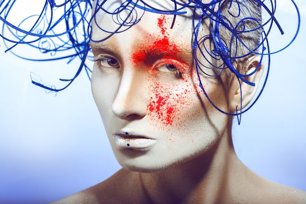 Sexuelle Frau mit Körperkunst und Neonpulver auf blauer Oberfläche
