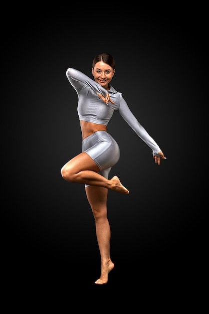 Sexy brünettes Mädchen mit schlanker Figur in Leggings posiert im Studio auf schwarzem Hintergrund