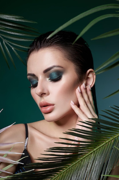 Sexy Frau des tropischen Porträts in der Blätterpalme. Hellgrünes Make-up, Schatten von Palmblättern auf Mädchengesicht. Schönes Make-up