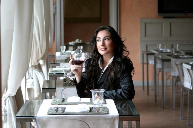 Sexy Frau, die Rotwein in einem Luxusrestaurant trinkt