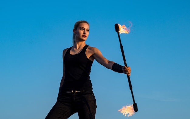 Sexy Frau Feuermanipulator führen flammenden Schlagstock wirbelnden Abend blauer Himmel im Freien gefährlich