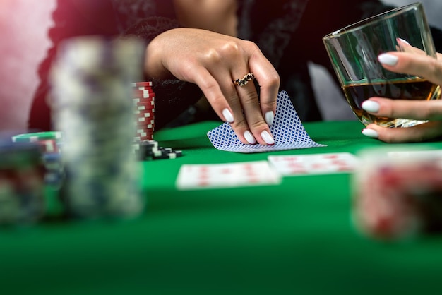 Sexy Frau mit Pokerkarten und Chips in den Händen, die am Tisch Poker spielen