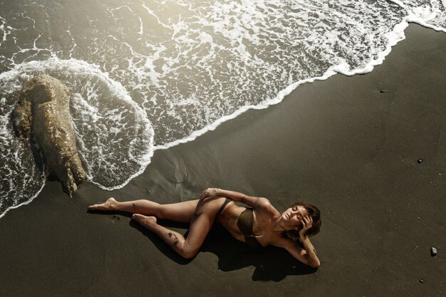 Sexy Frau mit schönem Körper liegt am Strand