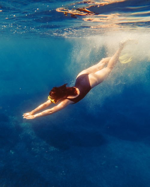 Sexy Frau schwimmt unter Wasser in Tauchermaske mit Flossen Sommerurlaub