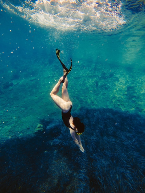 Sexy Frau schwimmt unter Wasser in Tauchermaske mit Flossen Sommerurlaub