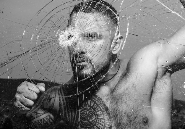 Foto sexy gángster hombre peligroso criminal hooligan tipo en vidrio de bala agrietado