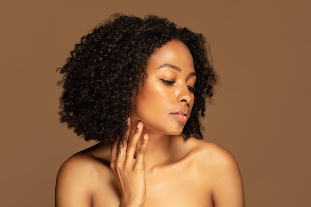 Sexy halbnackte afroamerikanische junge Frau berührt ihren Kiefer
