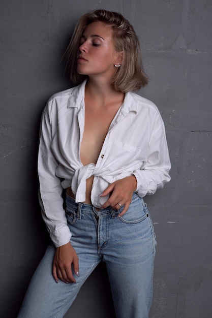 Sexy joven rubia con una figura hermosa en jeans y una camisa desabrochada