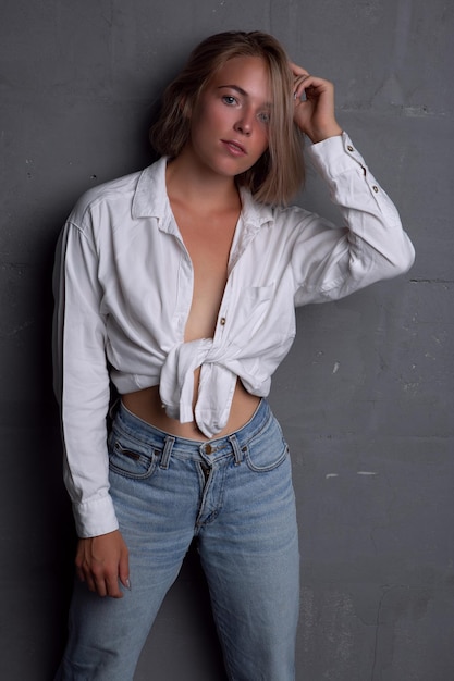 Sexy junge Blondine mit schöner Figur in Jeans und aufgeknöpftem Hemd