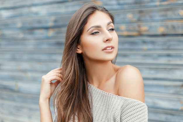 Sexy junge schöne Frau in einem Vintage grauen Pullover nahe der blauen Holzwand