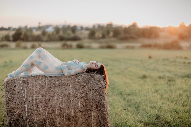 Foto sexy junges nacktes mädchen oben ohne auf einem heuhaufen auf einem feld im sommer liegend. der effekt einer kleinen filmkörnung wurde hinzugefügt