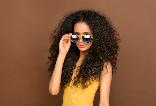 Sexy junges schwarzes Mädchen mit langen lockigen Haaren, die trendige Sonnenbrillen tragen