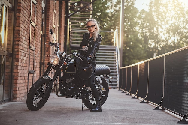 Sexy kurvige Frau posiert auf ihrem schwarzen Fahrrad auf der Straße und trägt stylische Kleidung.