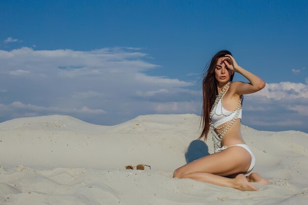 Sexy Mädchen im Sand in einem weißen Bikini