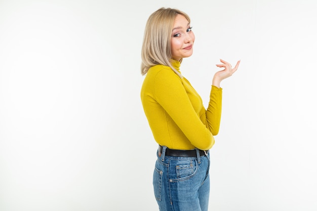 Sexy Mädchen in einer eng anliegenden gelben Bluse und Jeans niedlich lächelt auf einem weißen Hintergrund mit Kopienraum