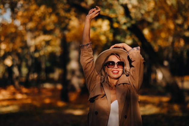 Sexy Mädchen in Mantel und Hut in einem sonnigen Park im Herbst