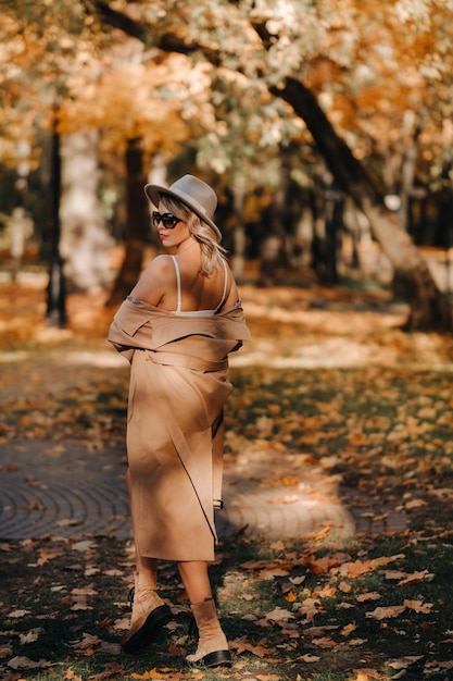 Sexy Mädchen in Mantel und Hut in einem sonnigen Park im Herbst