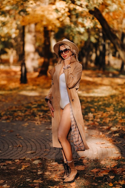 Sexy Mädchen in Mantel und Hut in einem sonnigen Park im Herbst