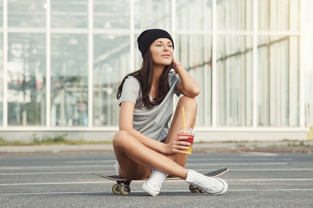 Sexy Mädchen sitzt auf dem Skateboard