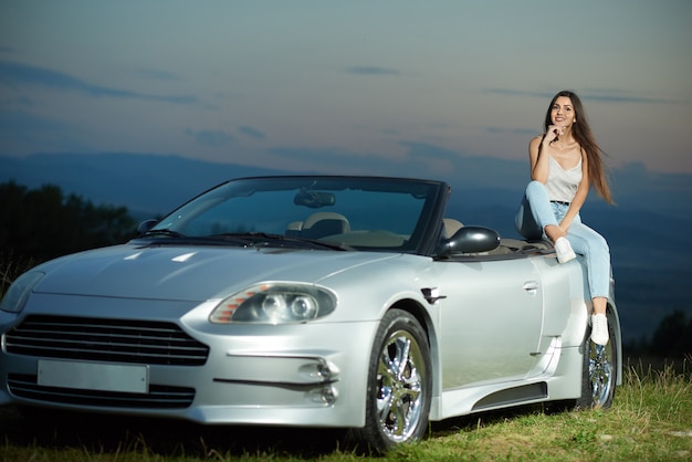 Sexy Model posiert auf luxuriösem silbernem Cabriolet.