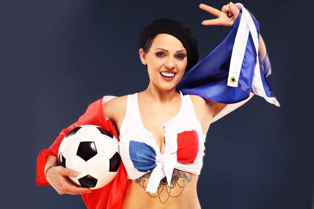 sexy, mujer, llevando, bandera francesa, y, tenencia, fútbol