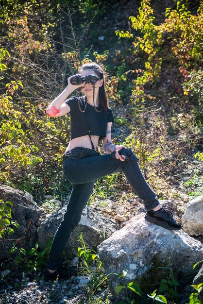 Sexy mujer soldado está usando los prismáticos en la naturaleza. guerrero