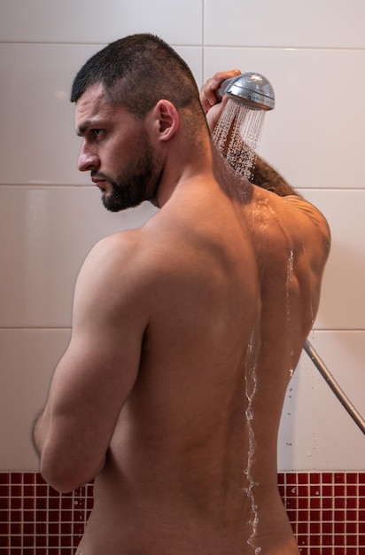 Sexy muskulöser Mann duscht im Badezimmer. Sexy Kerl wäscht nackten Körper. Männliche Körperpflege. Schönheitsroutine