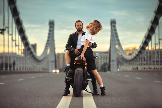 Sexy pareja de ciclistas en la motocicleta vintage. Retrato de estilo de vida al aire libre, en una cita romántica.