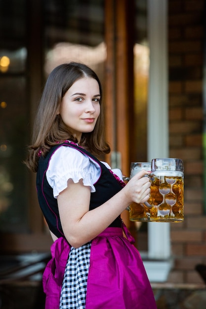 Foto sexy russische frau im bayerischen kleid hält bierkrüge