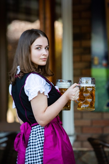 Foto sexy russische frau im bayerischen kleid hält bierkrüge