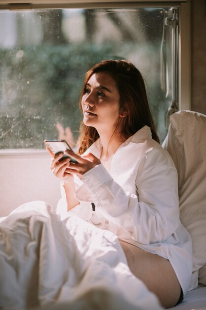 Sexy schöne Frau mit einem Smartphone im Bett