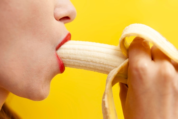 Sexy und intimes Blowjob-Konzept Frau leckt und nimmt Banane in den Mund auf gelbem Hintergrund