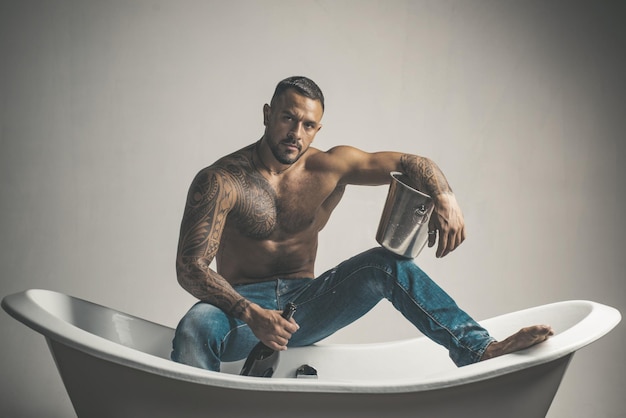 Sexy verführerischer Mann sitzt auf Badewanne im Badezimmer Männer Urlaub mit Champagner Private Sexparty