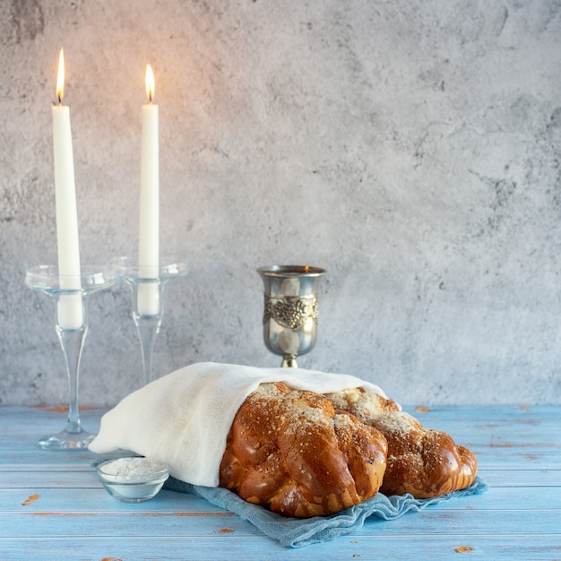 Foto shabat shalom - pan jalá, vino de shabat y velas en la mesa de madera