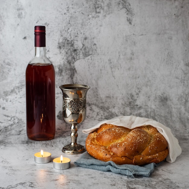 Shabat shalom - pão chalá, vinho do shabat e velas em cinza.