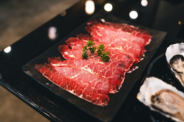 Shabu de carne fatiada em um prato preto em um restaurante, carne japonesa fatiada