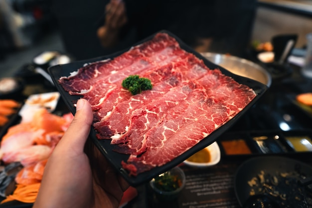 Shabu de carne fatiada em um prato preto em um restaurante, carne japonesa fatiada