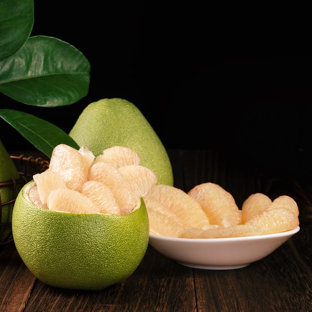 Shaddock de toranja de pomelo descascado fresco com folhas verdes na mesa de prancha de madeira escura Frutas sazonais perto do festival de meados de outono fechar espaço de cópia