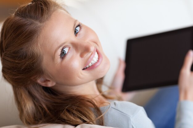 Shadowing sonriente mujer en el sofá con tableta