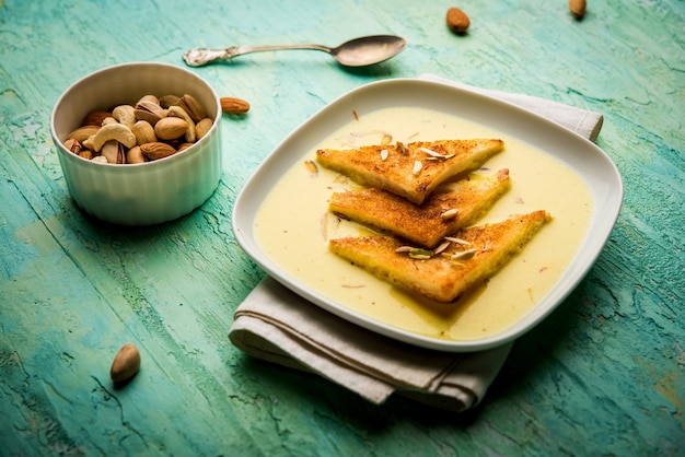 Shahi Tukra oder Tukda oder Double Ka meetha ist ein indischer Brotpudding aus gebratenen Brotscheiben, die in tollwütiger oder süßer Safranmilch getränkt sind, garniert mit Trockenfrüchten, selektiver Fokus