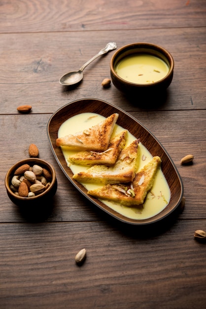 Shahi tukra ou tukda ou Double ka meetha é um pudim de pão indiano doce de fatias de pão frito embebido em leite com raiva ou doce de açafrão guarnecido com frutas secas, foco seletivo