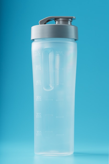 Shaker es un vaso de batido de plástico vacío sobre una superficie azul